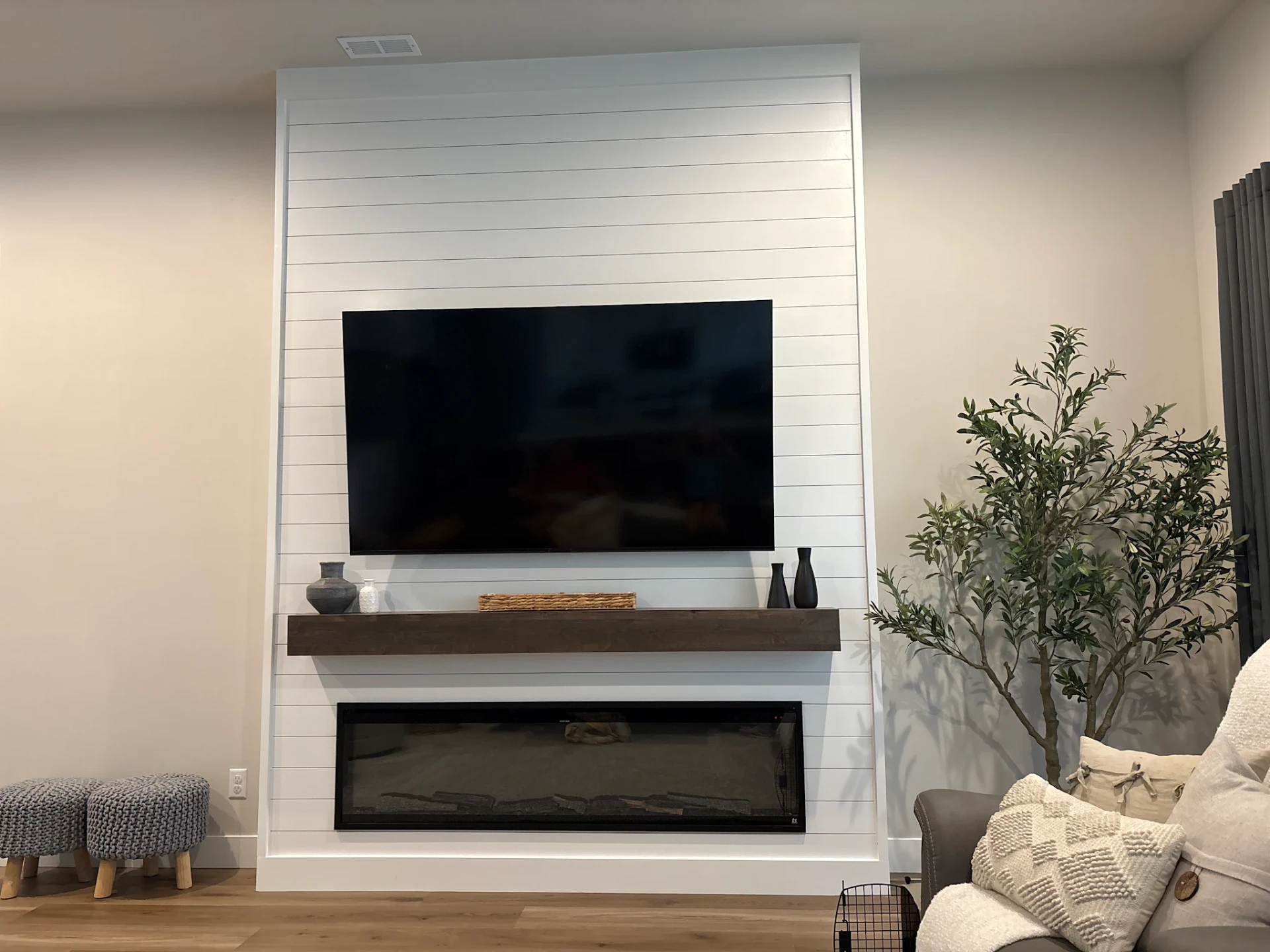 Floor-to-ceiling white shiplap fireplace surround with a stained wood mantel