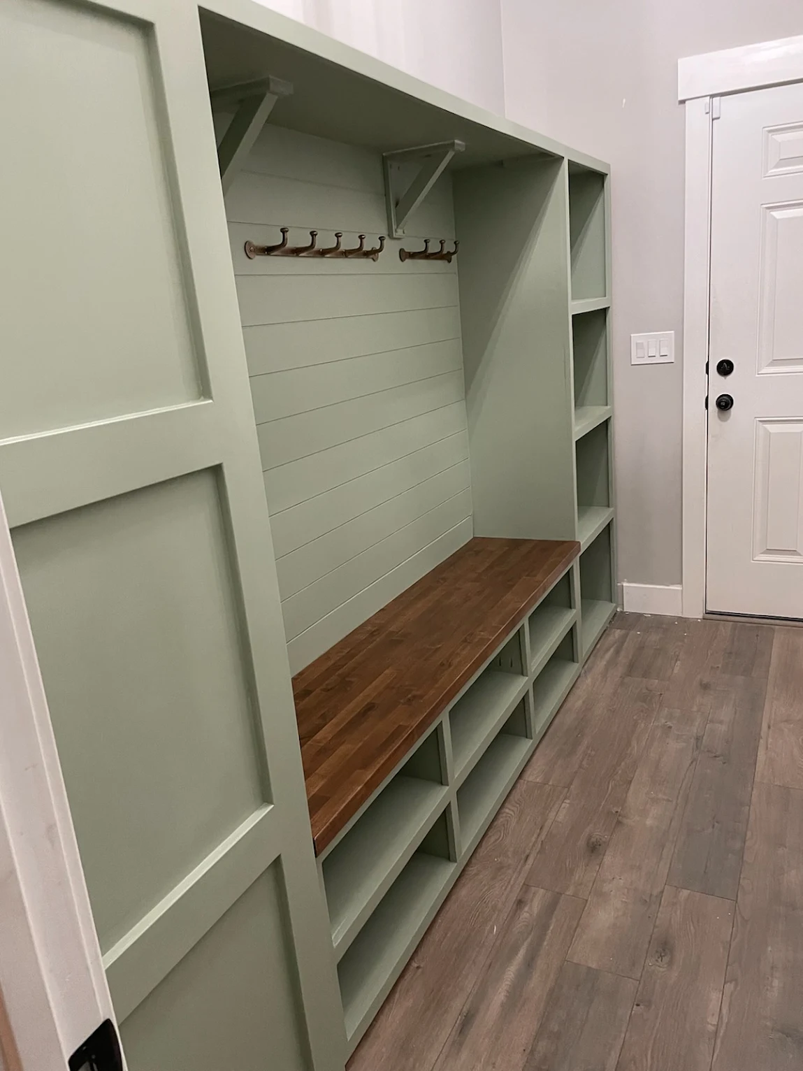 Sage green custom mudroom bench with shiplap back, hooks and cubby storage