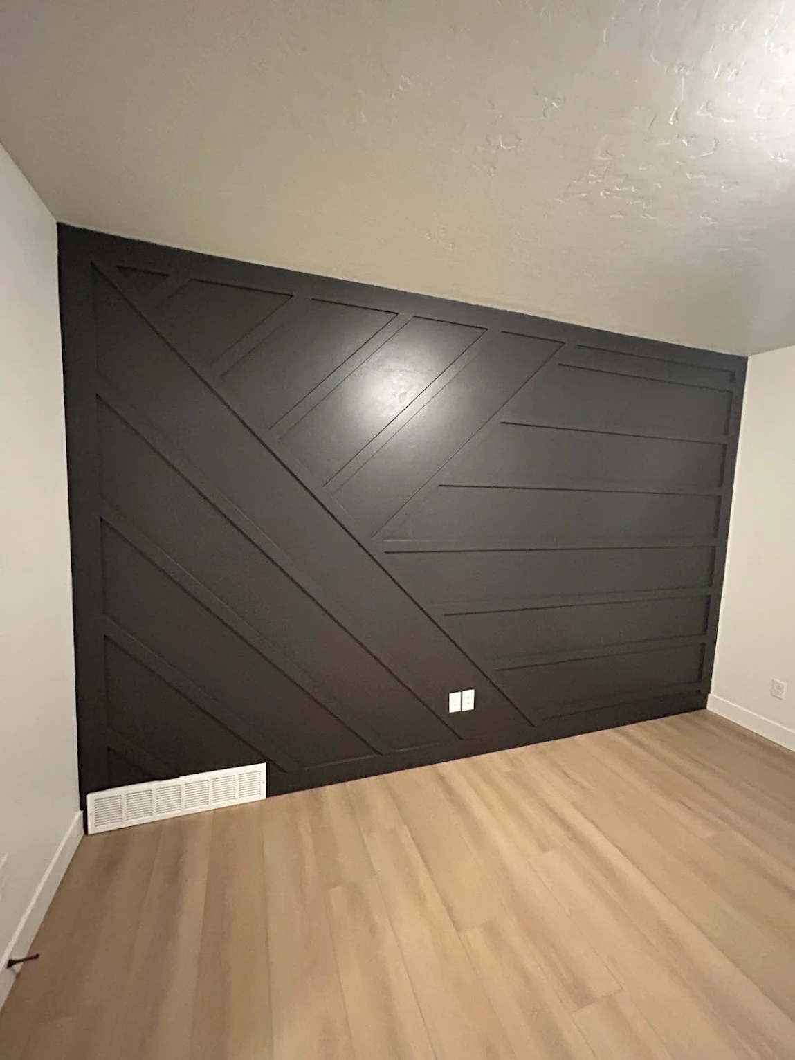 Charcoal geometric board and batten accent wall in a bedroom