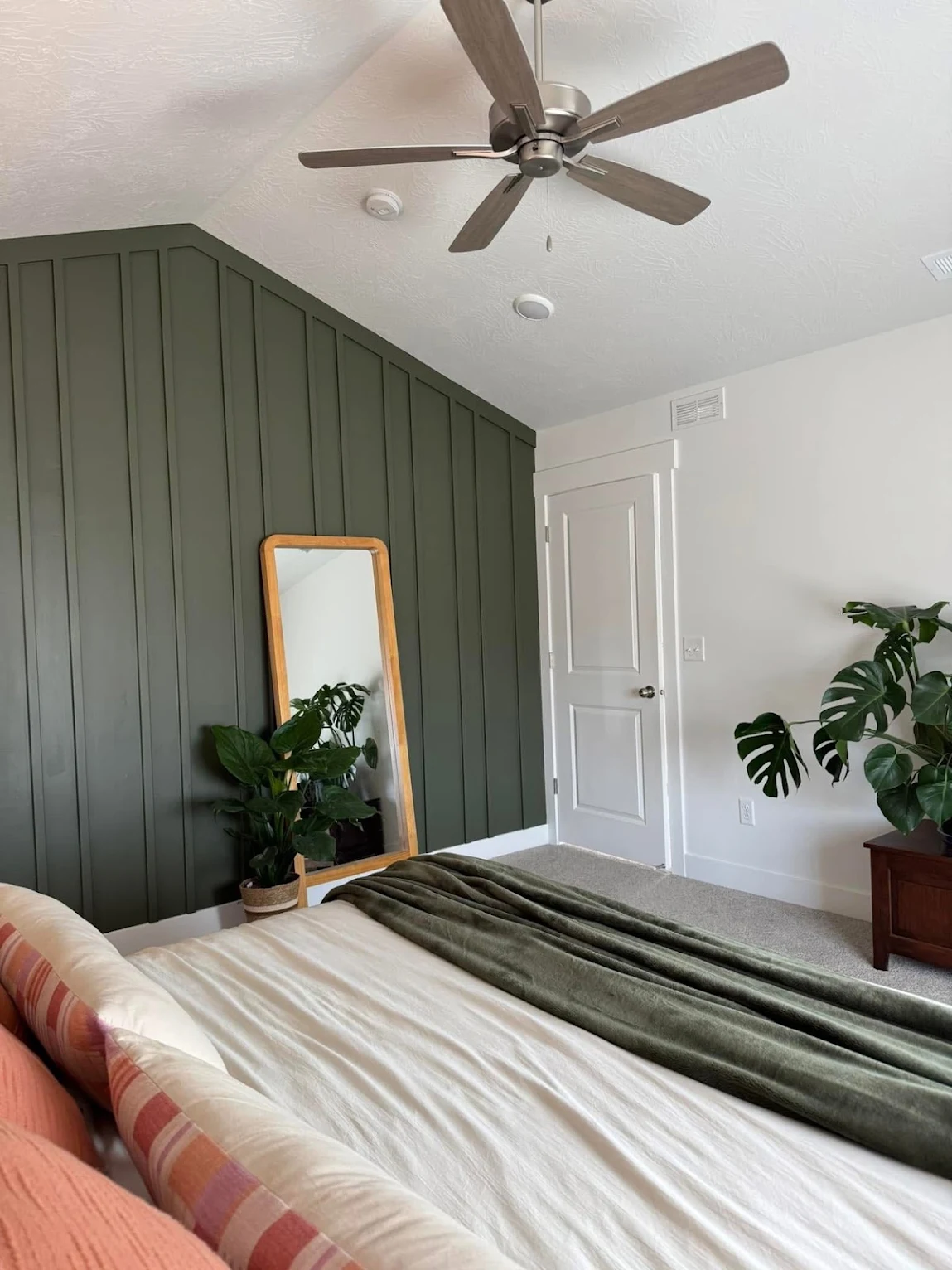 Deep green vertical board and batten accent wall in a primary bedroom